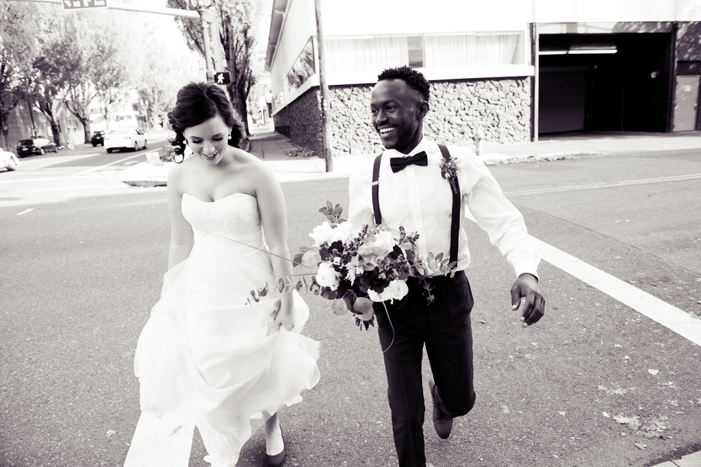 bride and groom walk along burnside in portland while groom hold's the bouquet