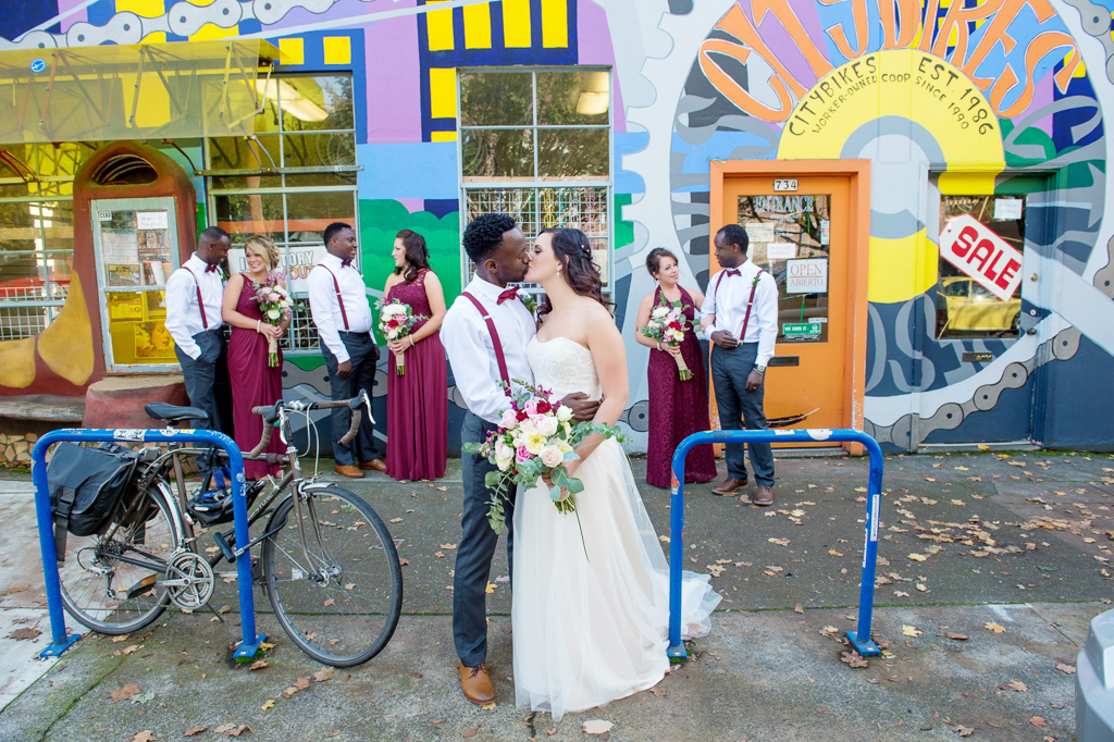 the wedding party wearing maroon stand under a brightly colored mural near burnside