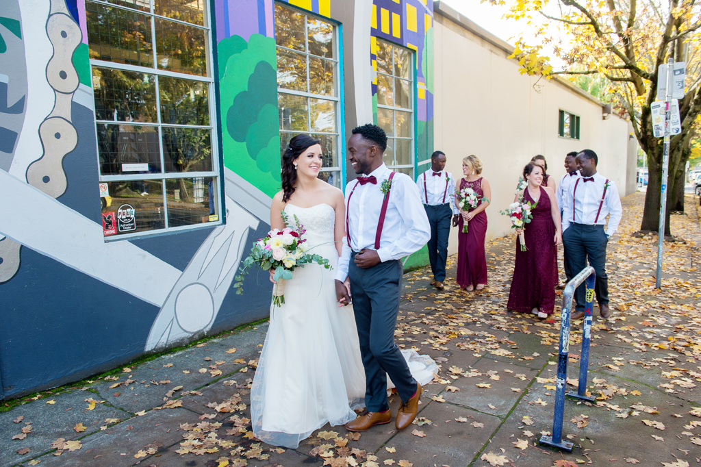 the wedding party wearing maroon walk under a brightly colored mural near burnside