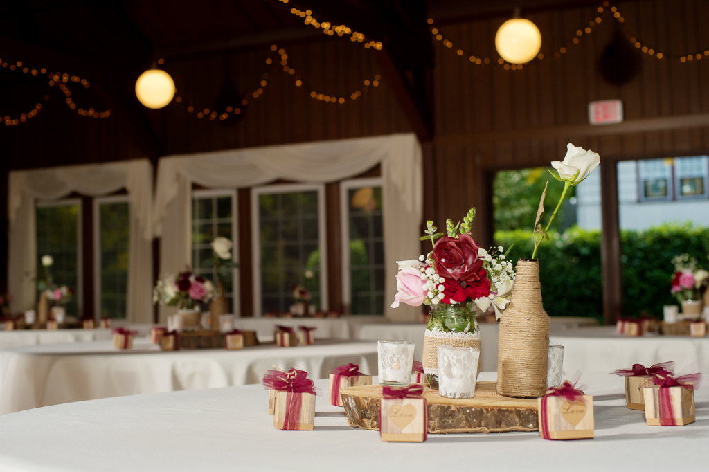 burlap twine wrapped bottles and glasses hold flowers for wedding reception decor