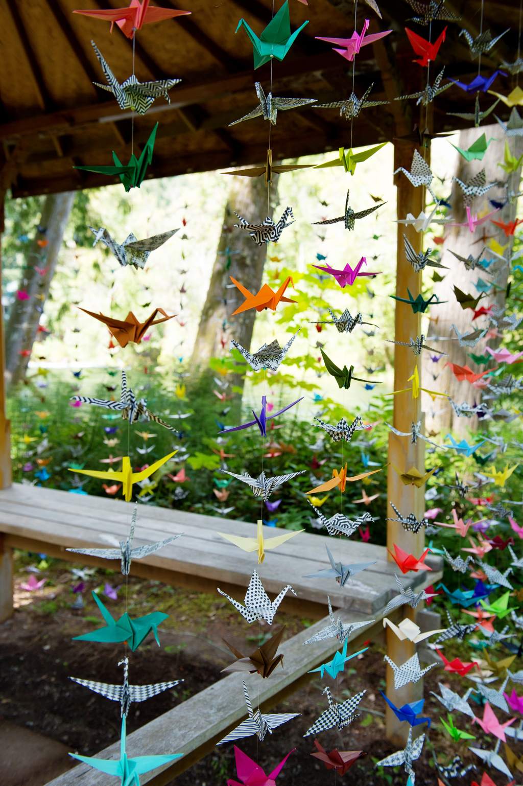 colorful paper origami cranes hang from string on a gazebo for the wedding ceremony arbor