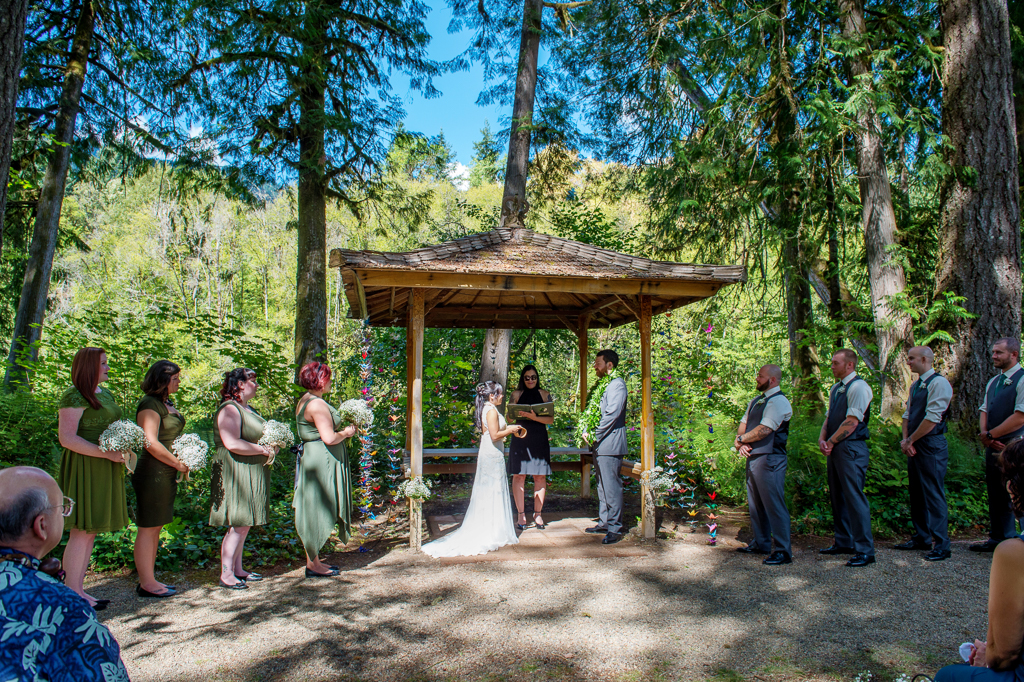a wedding ceremony under the gazebo at loloma lodge covered in strings of colorful paper origami cranes