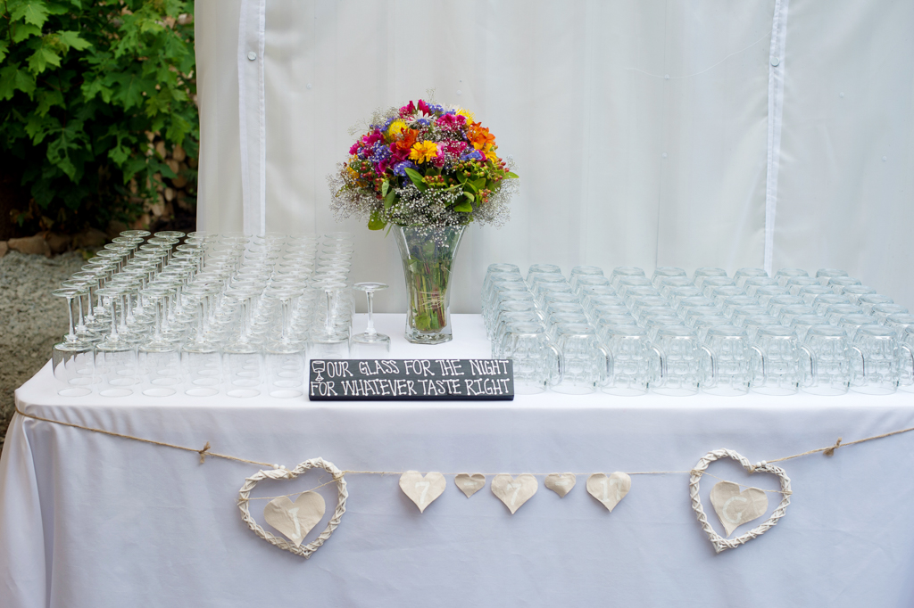 table that has a vase of flowers surrounded by a bunch of drinking glasses at the reception of a weddign in Thorburg Oasis