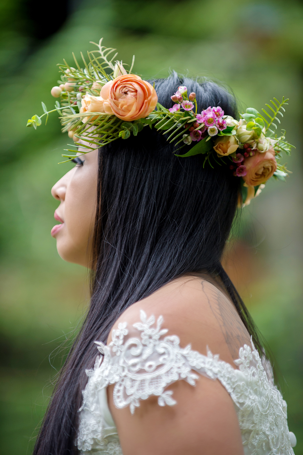 a bride wears a pretty flower crown with orange and pink flowers and small ferns