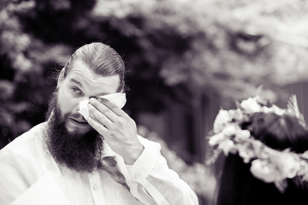 a groom wipes a tear from his eye with a handkerchief during his wedding
