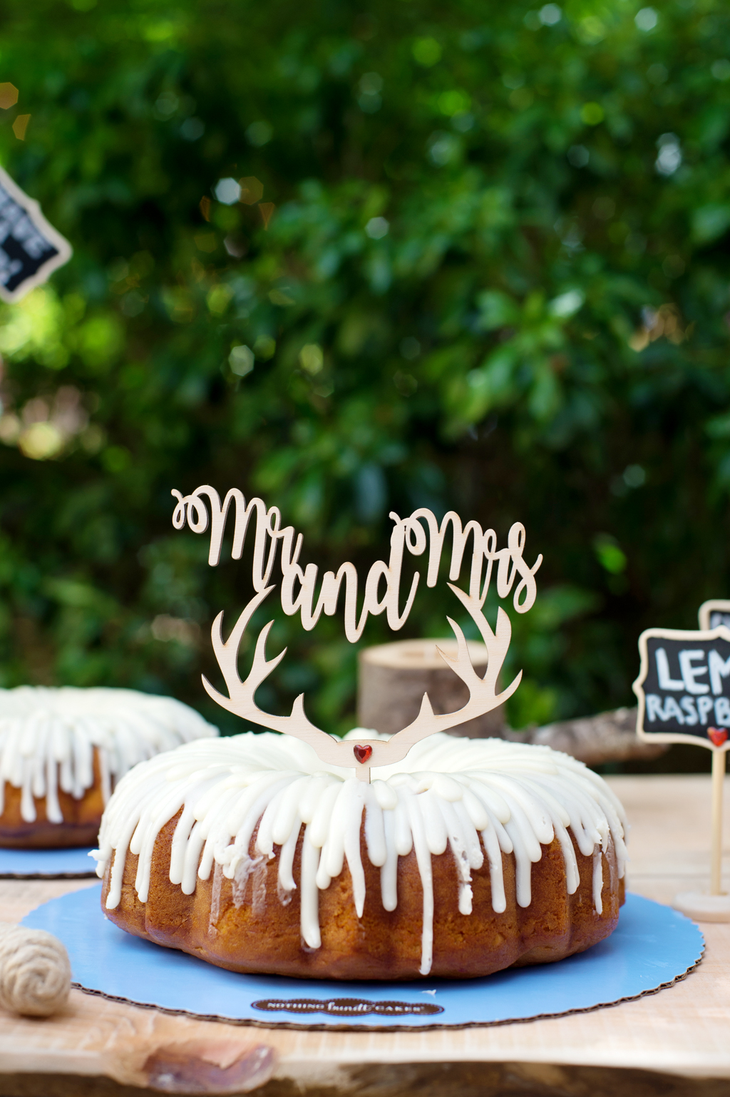 a mr and mrs antler cake topper sits atop a bundt cake with dripping white icing