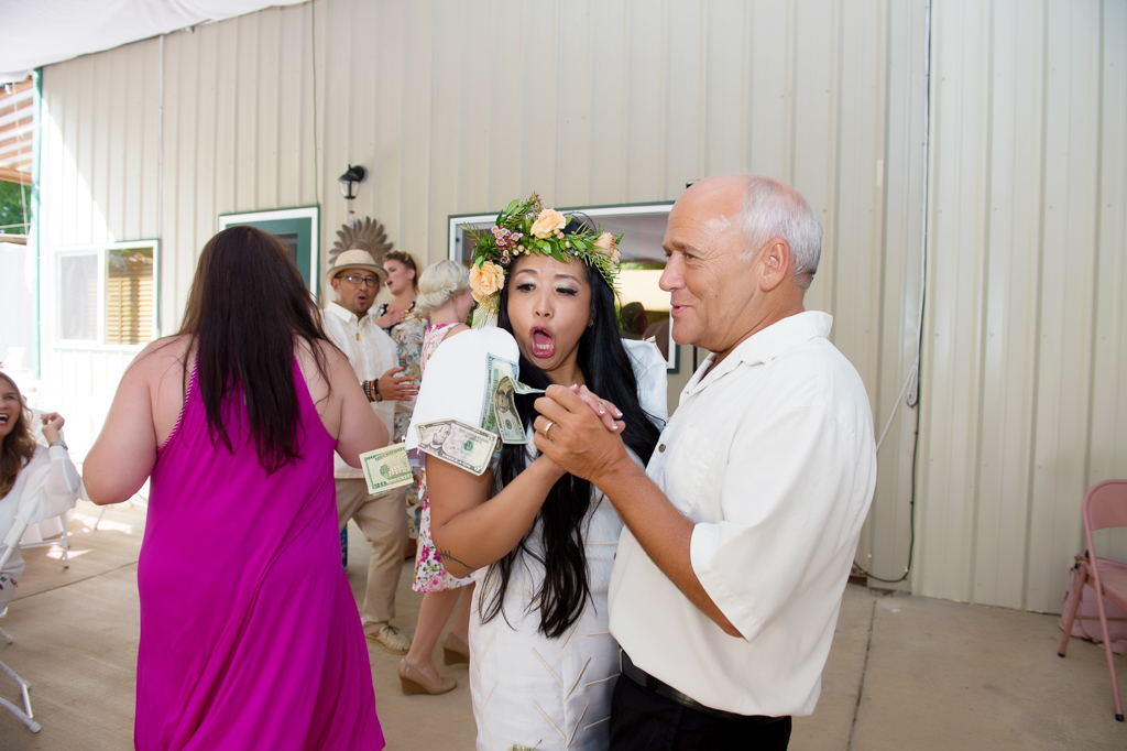 a bride covered in dollar bills dances the money dance at her wedding reception