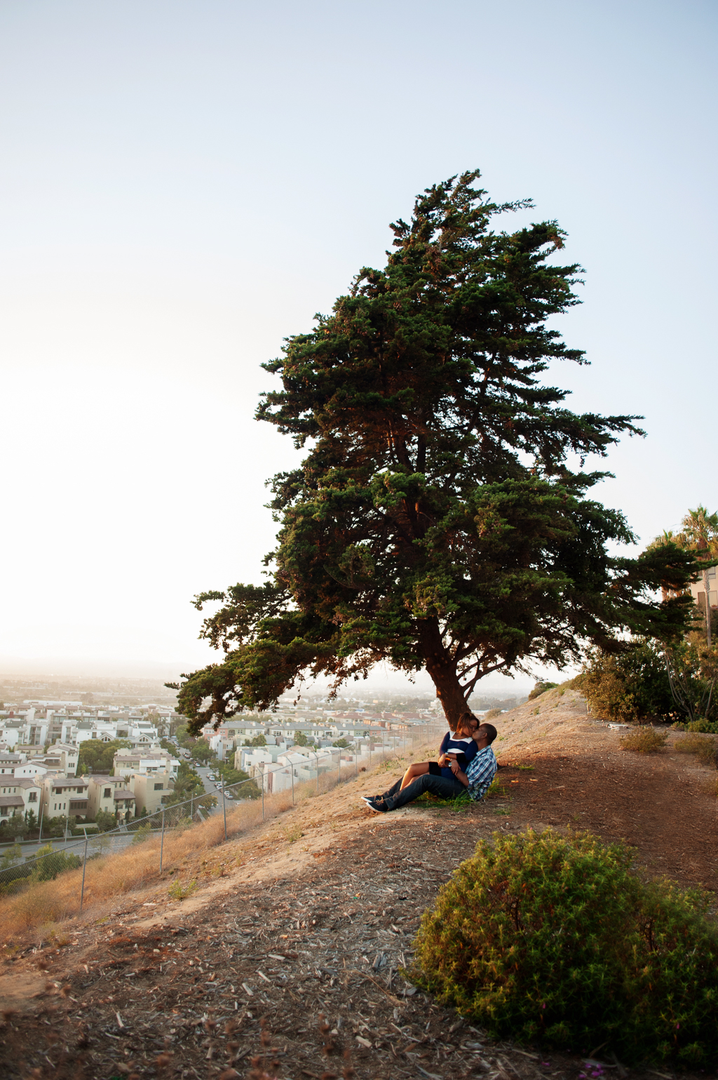a couple sit under a tree on the loyola marymount campus overlooking los angeles