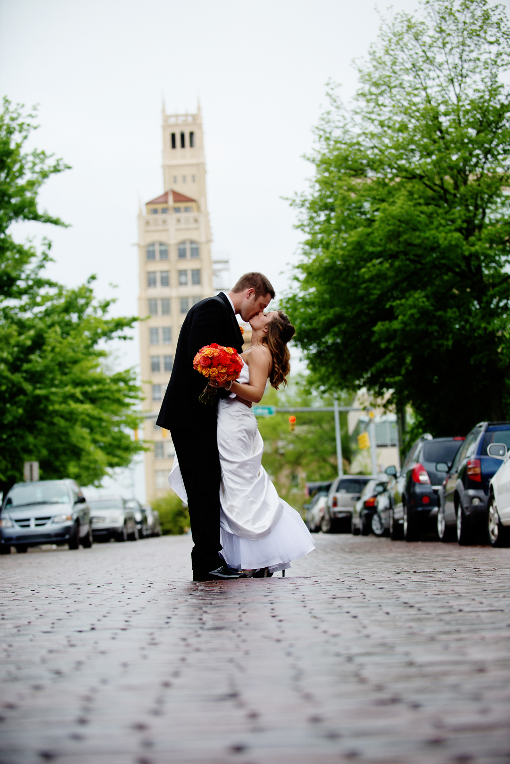 bride and groom kiss in the middle of a cobblestone street