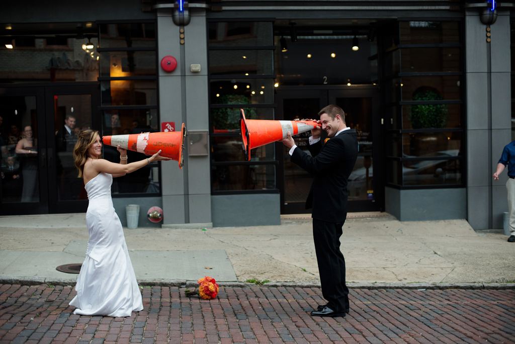 bride and groom look through traffic cones