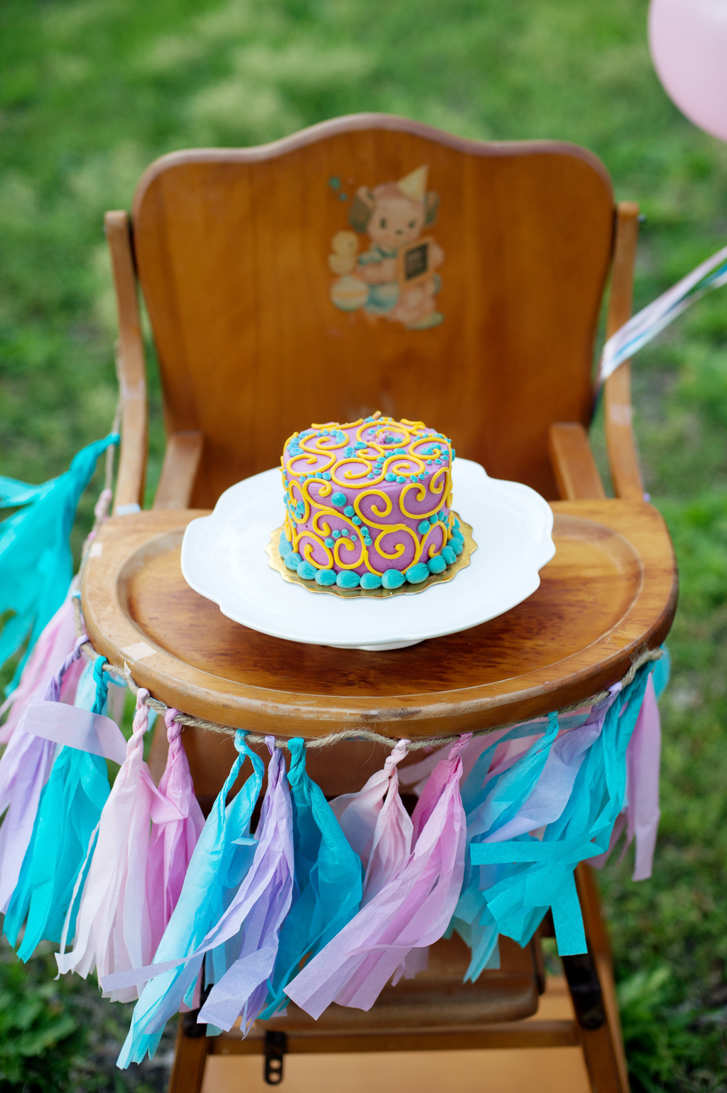 a pretty swirly birthday cake on a high chair with tassels