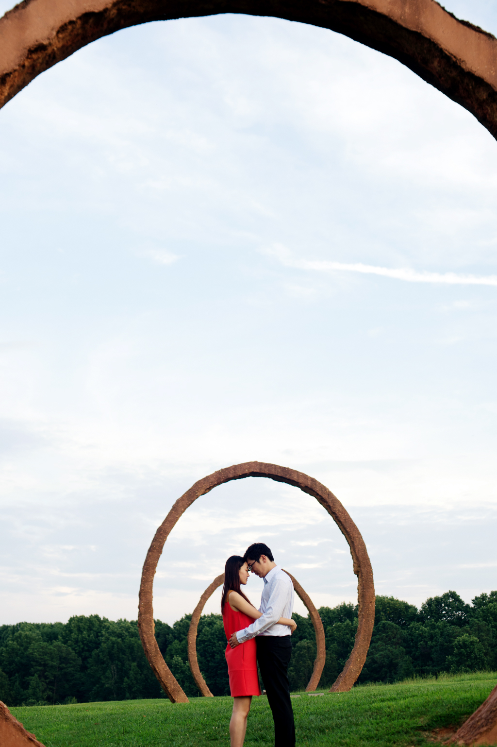 a couple embrace underneath the giant sculpture rings at ncma