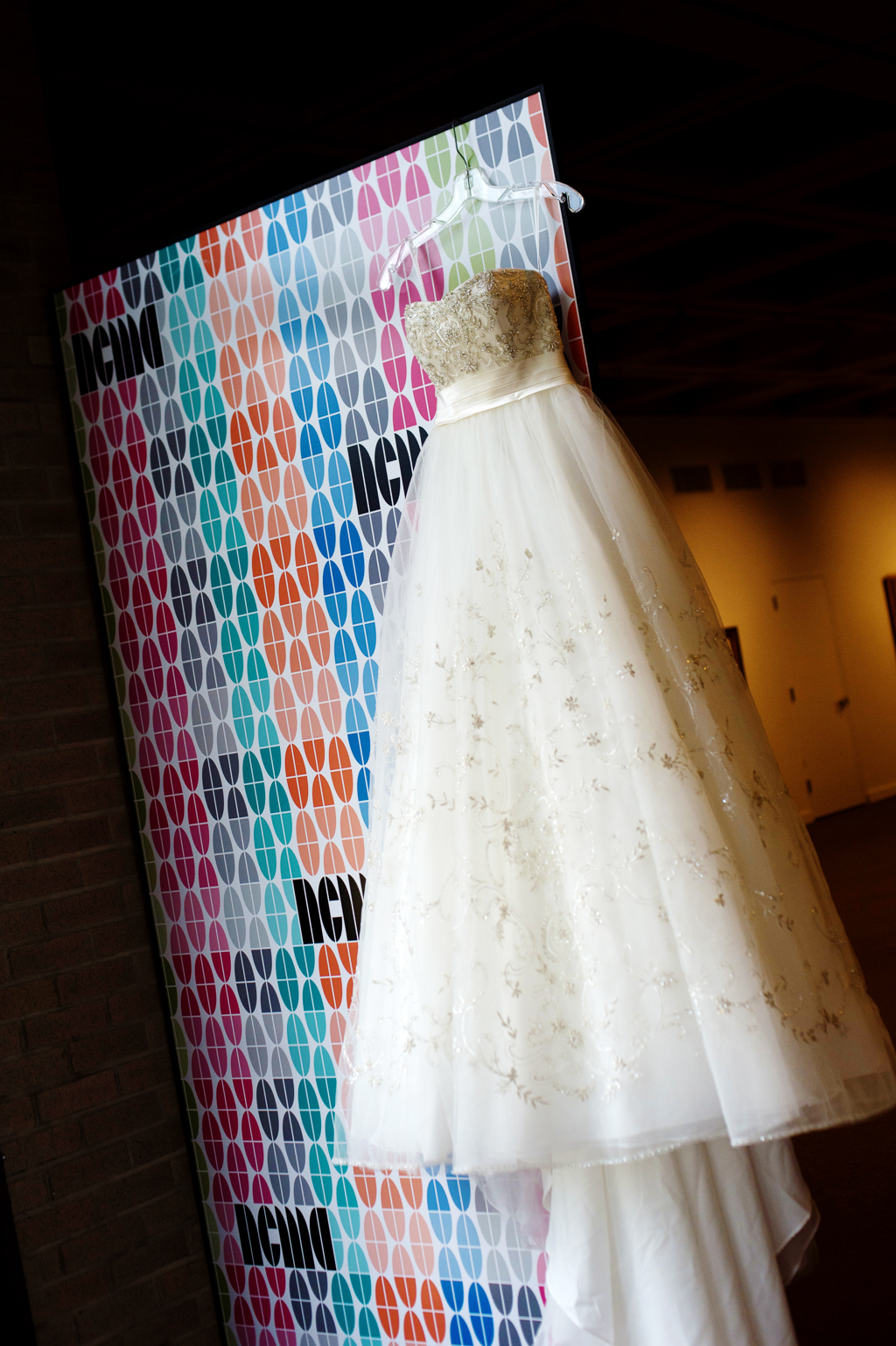 a wedding dress hangs on a colorful wall at ncma