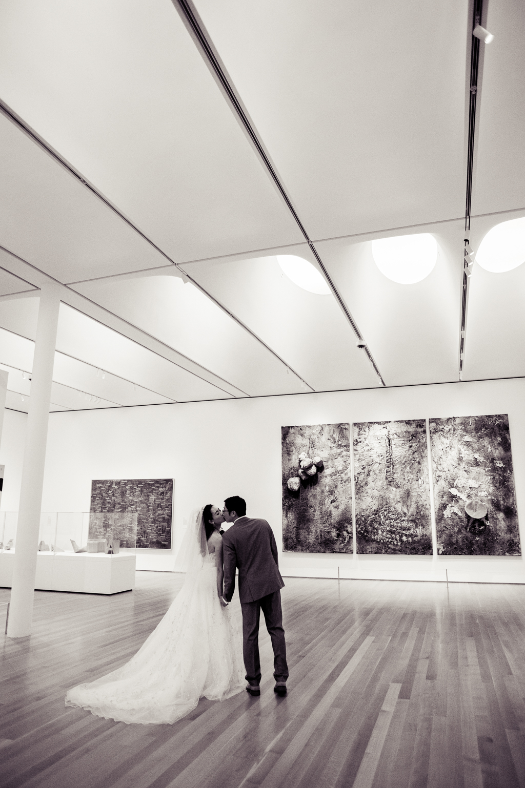 a bride and groom kiss as they walk through the art museum