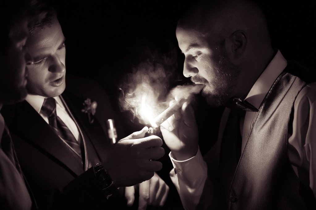 best man lights the groom's cigar at night