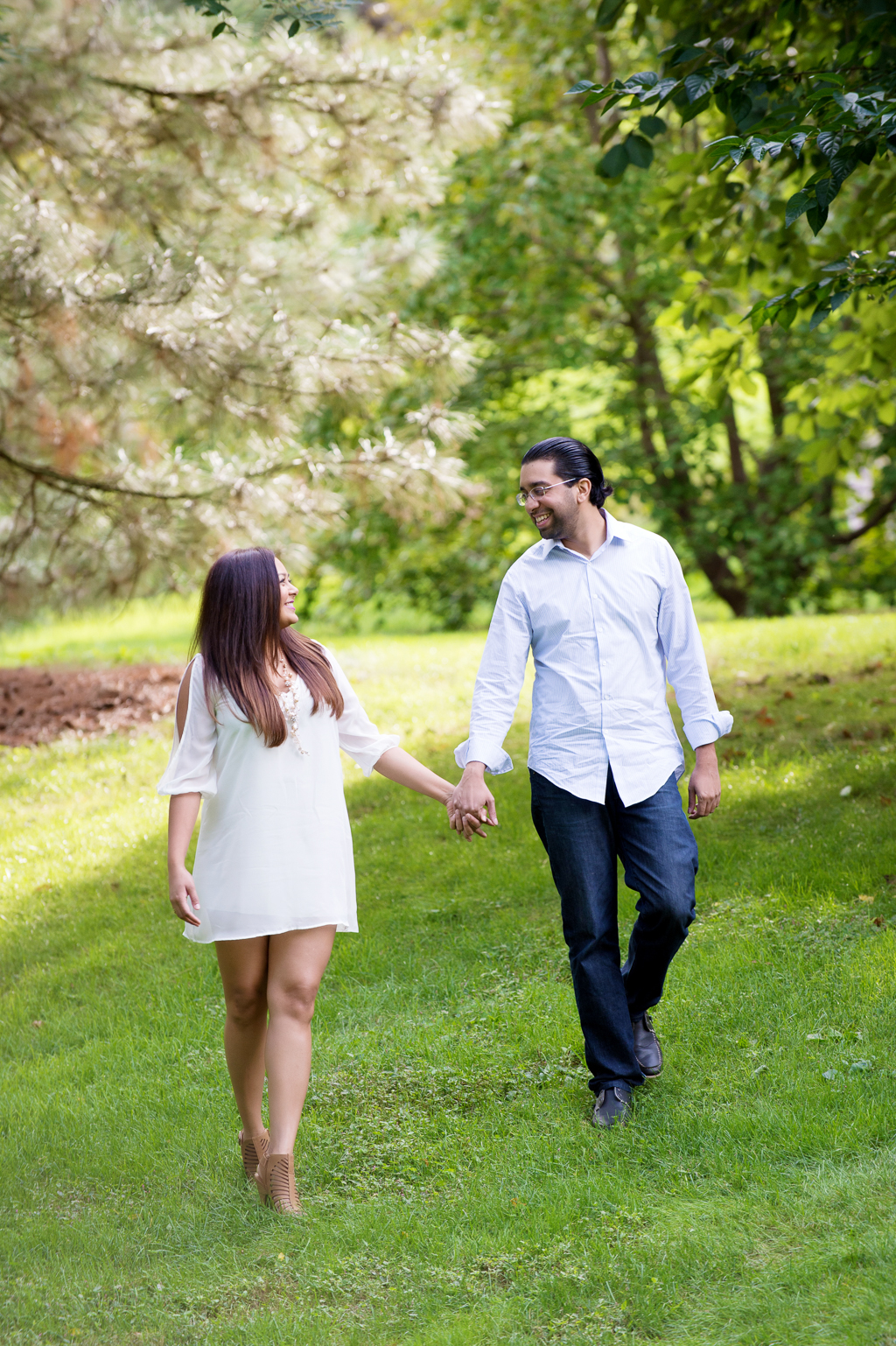 a couple holds hands and walks through bronx botanical garden