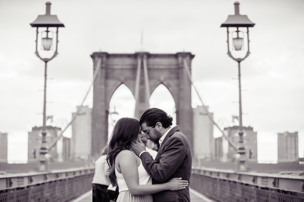 a man and woman embrace on the brooklyn bridge