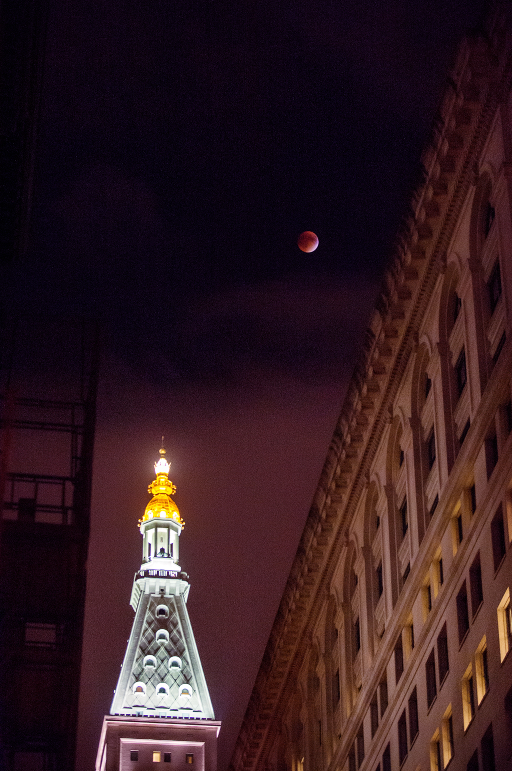 a lunar eclipse shows a red moon in the sky over nyc clock tower in gramercy park