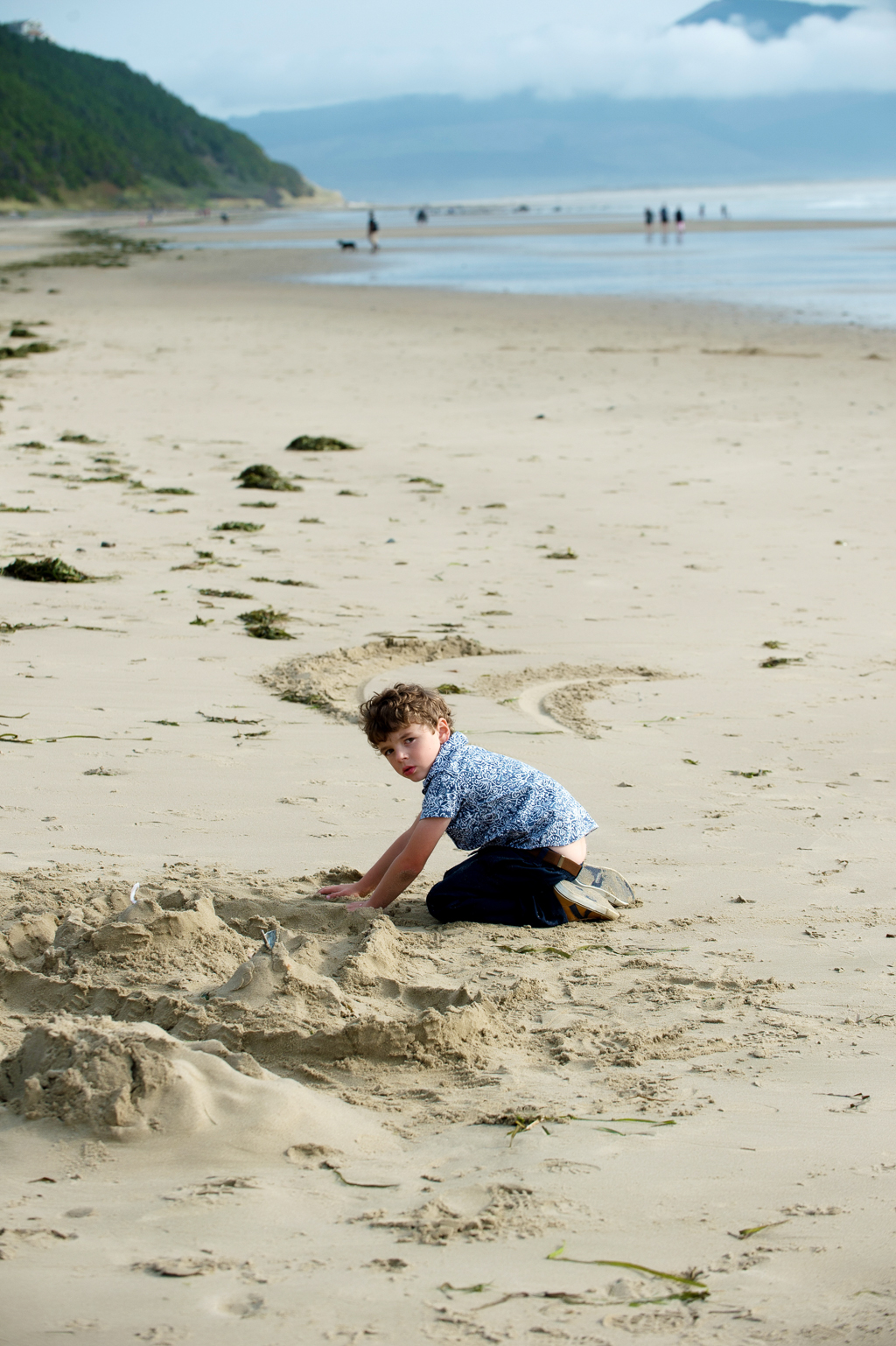 a little boy plays in the sand on the beach