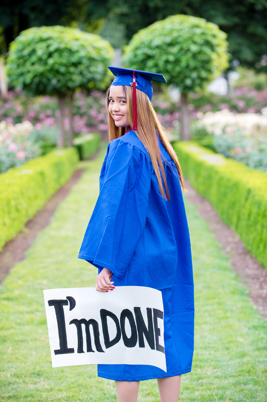 a high school senior wears her cap and gown and holds a sign that says I'm Done