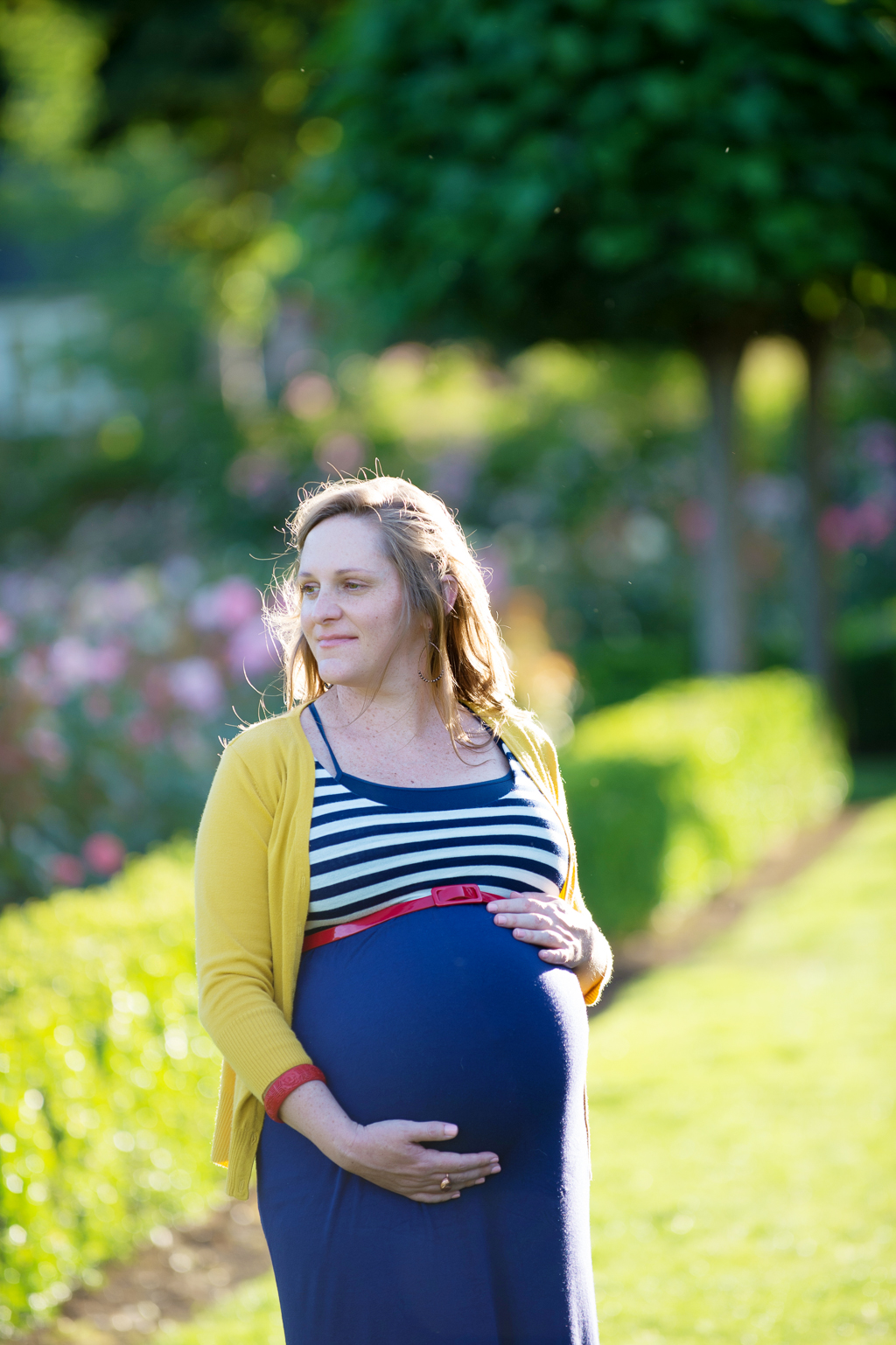 a pregnant woman holds belly wearing a blue red white and yellow dress