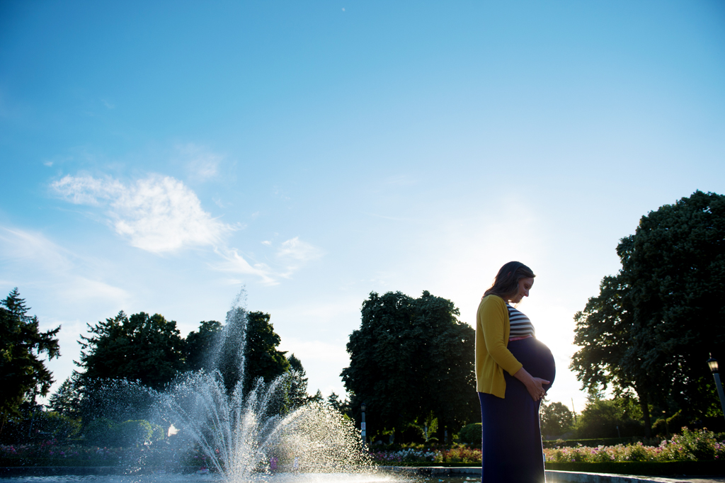 a silhouette of a pregnant woman in front of a fountain