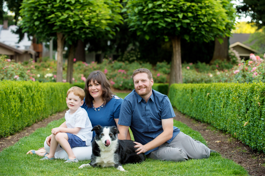 a family and their dog sit in the rose garden at peninsula park