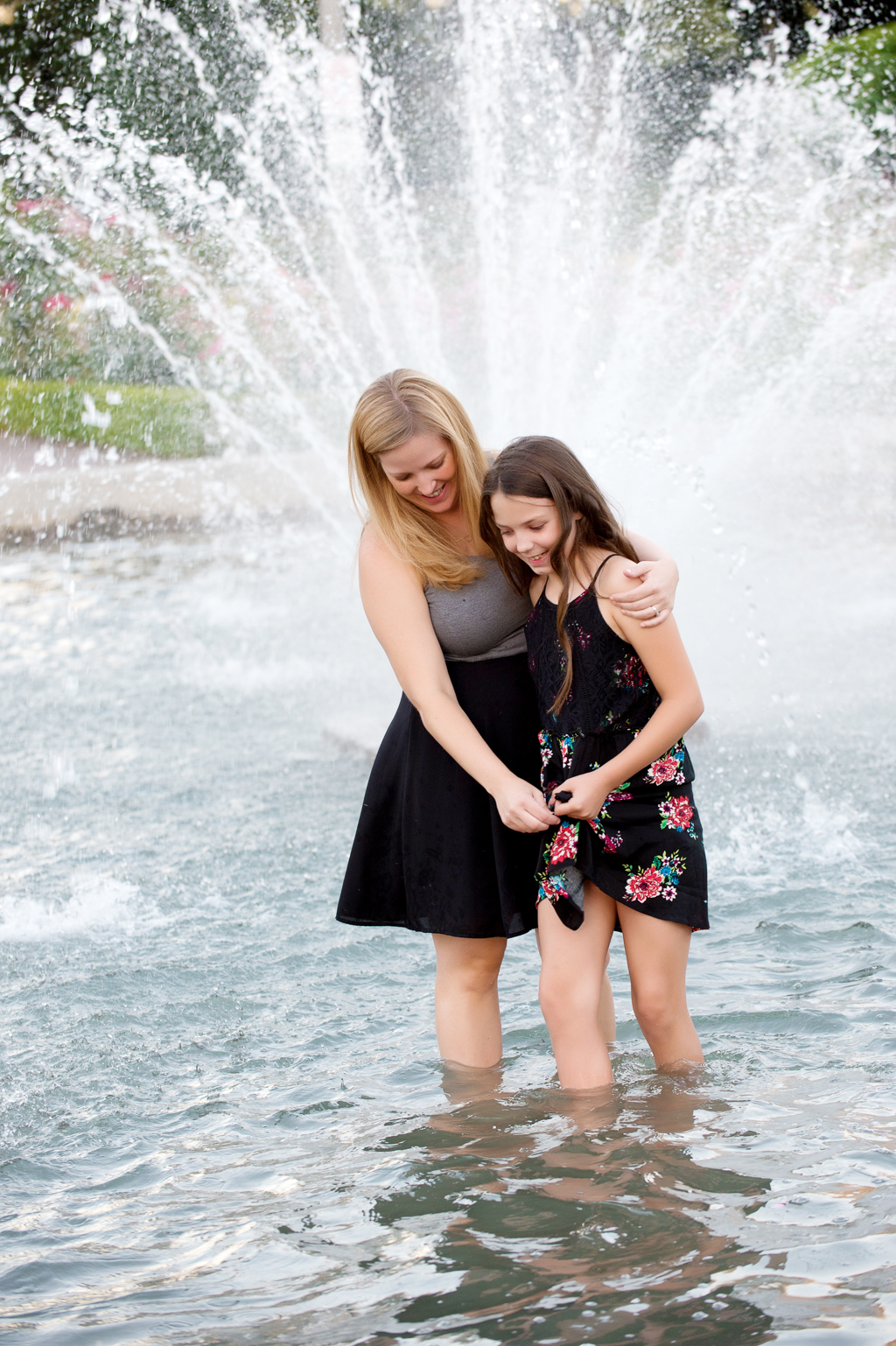 mom and daughter walk through water fountain