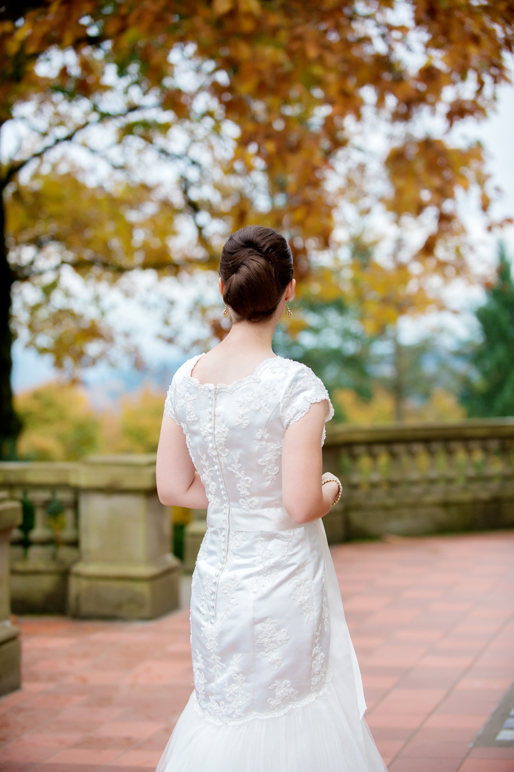 bride looks off pittock mansion porch into the colorful fall leaves