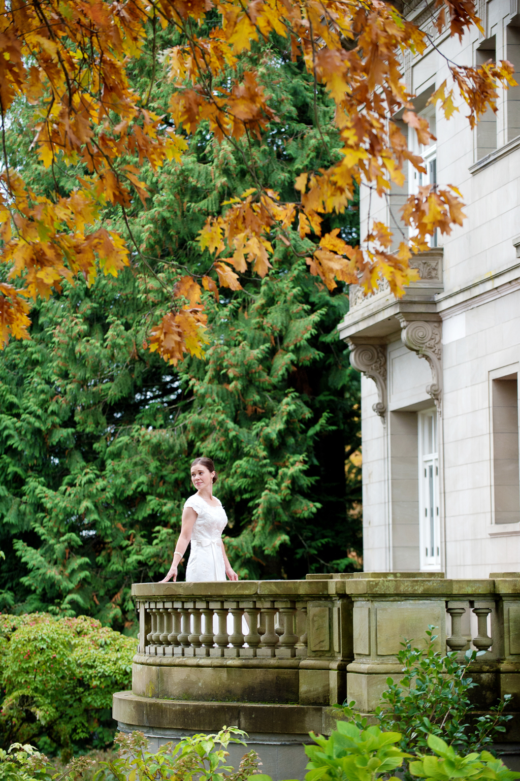 bride looks out over yard off of porch of pittock mansion