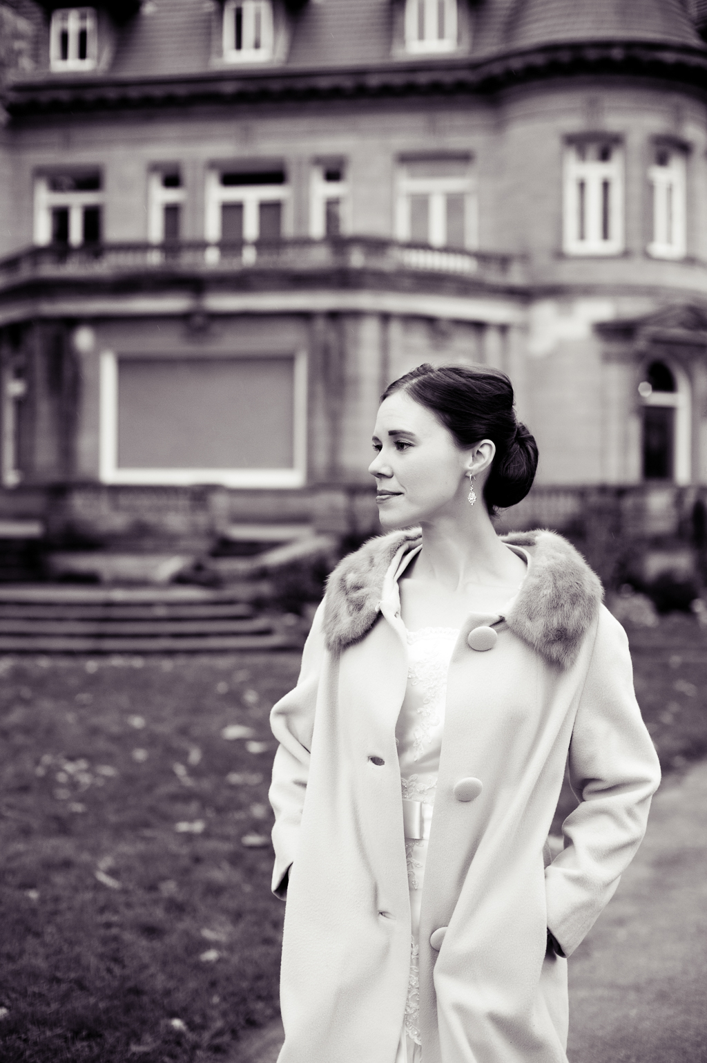 black and white portrait of a bride wearing a fur collared coat in front of pittock mansion