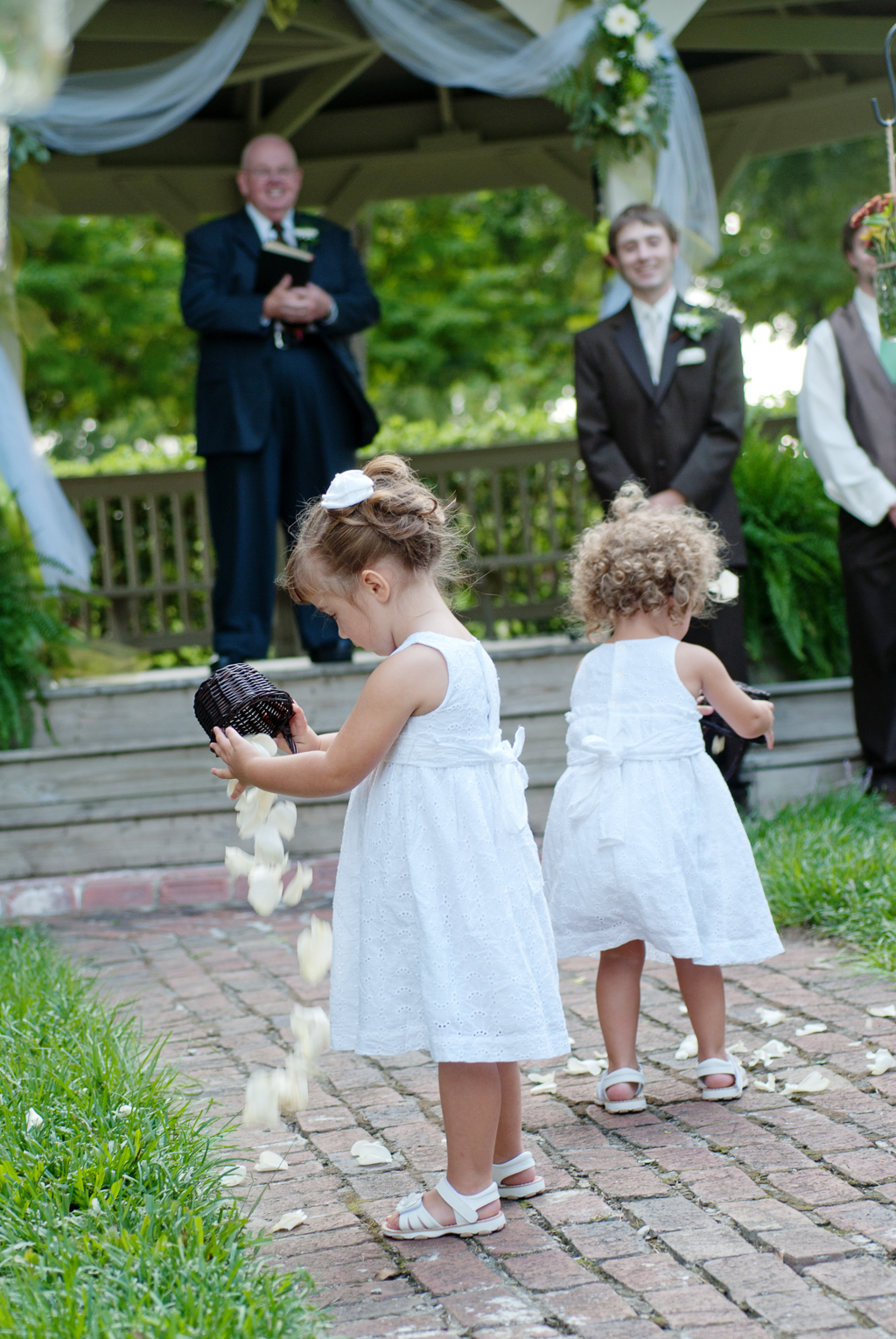flower girls pour flowers out of baskets at front of ceremony aisle