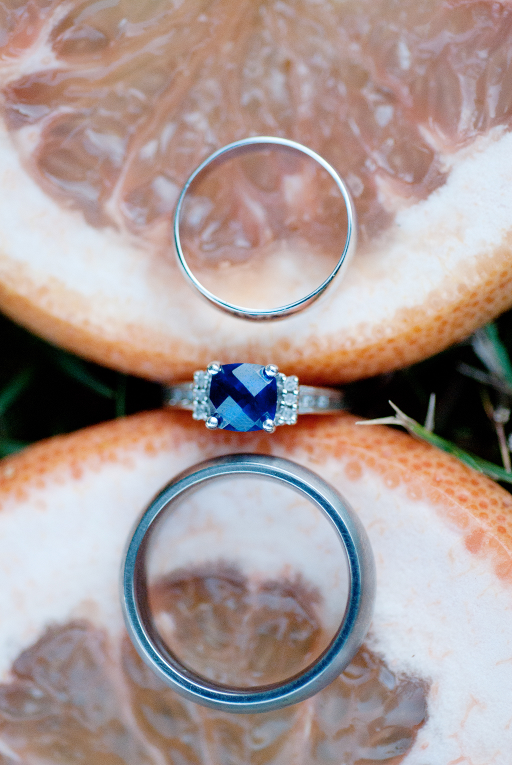 sapphire wedding ring held between two slices of orange