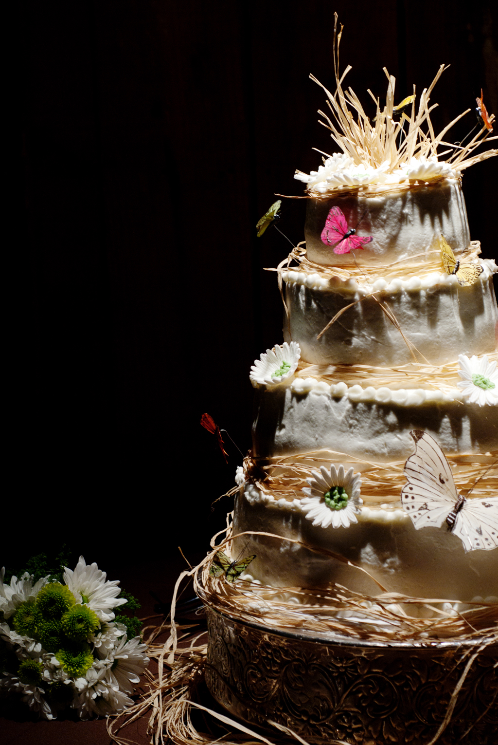 a wedding cake with hay, flowers, and butterflies
