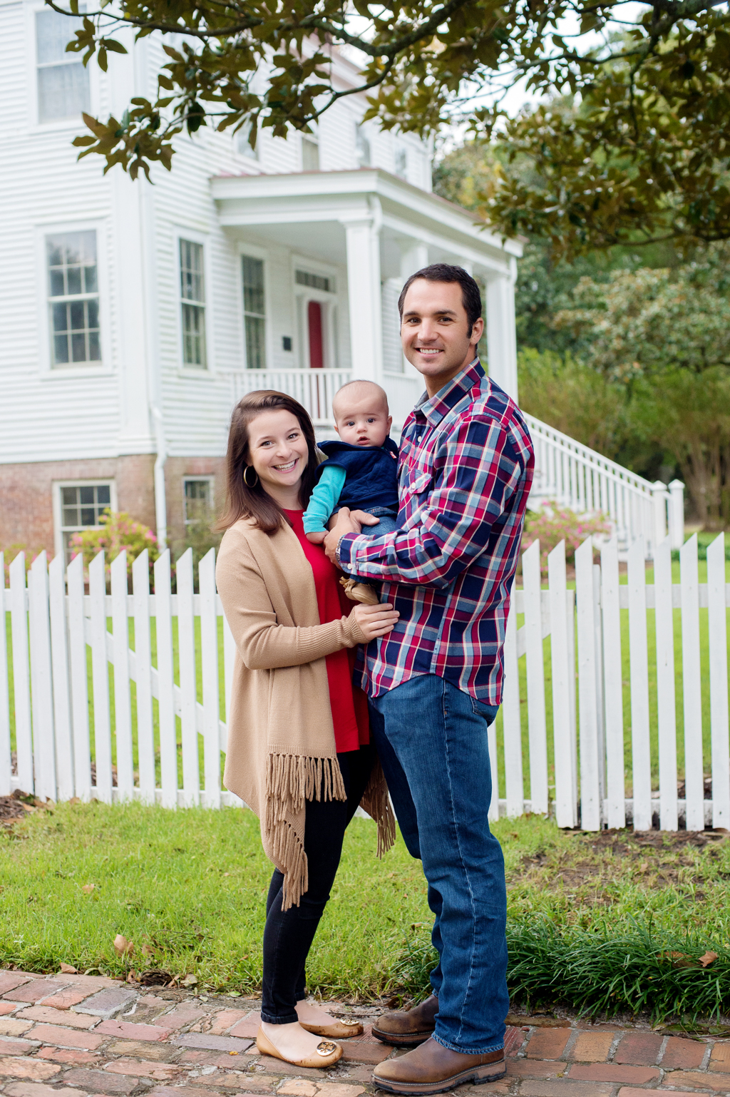 a family poses together with their baby boy in front of poplar grove plantation house