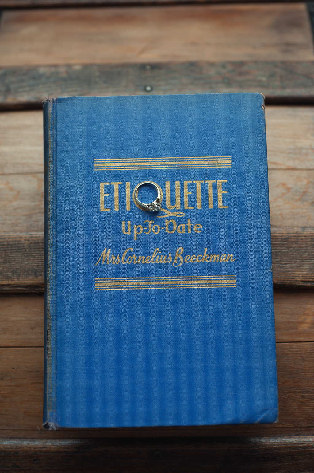 wedding ring sits on a book titled etiquette up to date