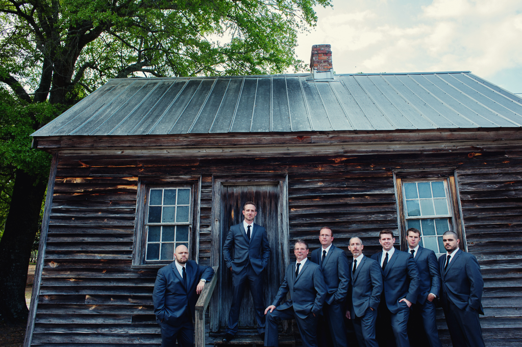 groomsmen stand outside of old cabin on plantation