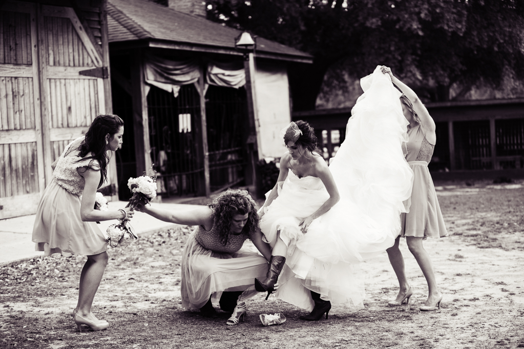 bridesmaids help bride with shoes and wedding dress