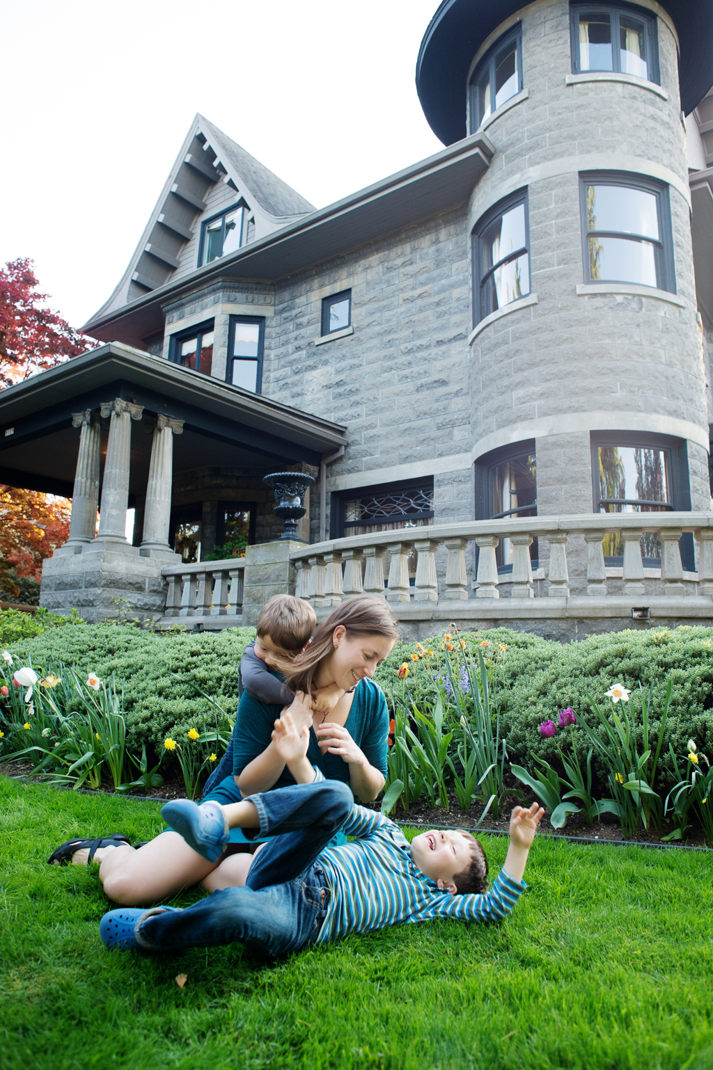 mom plays with her two sons in the yard with their old portland castle home in the background