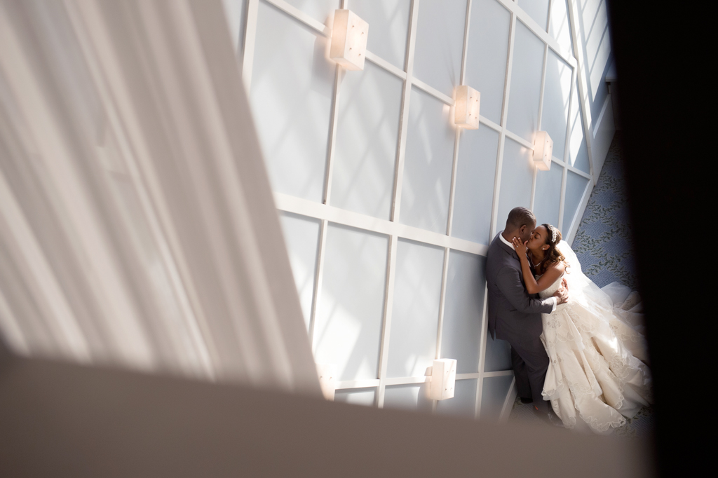 a bride and groom embrace and kiss leaning against a blue wall with white trim in the portofino hotel