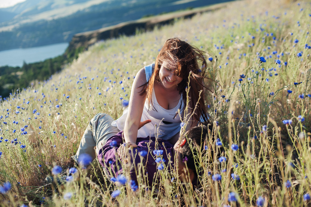 a couple plays in the tall grass and blue wildflowers at rowena crest