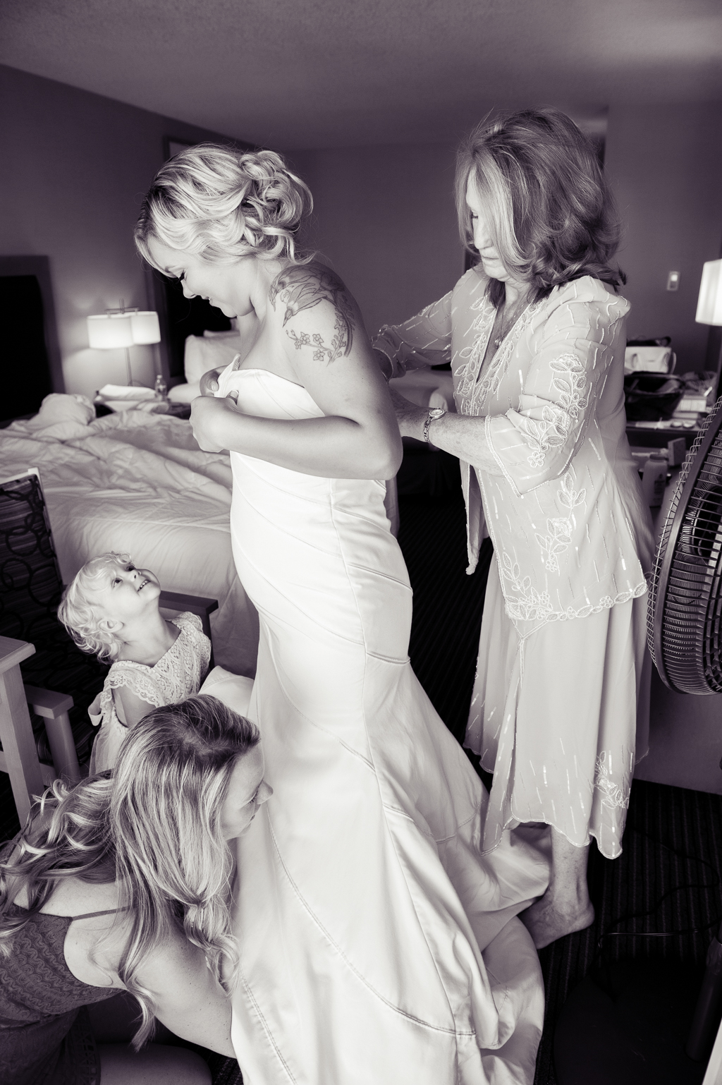 a young girl looks up at her mom as she puts on a wedding dress