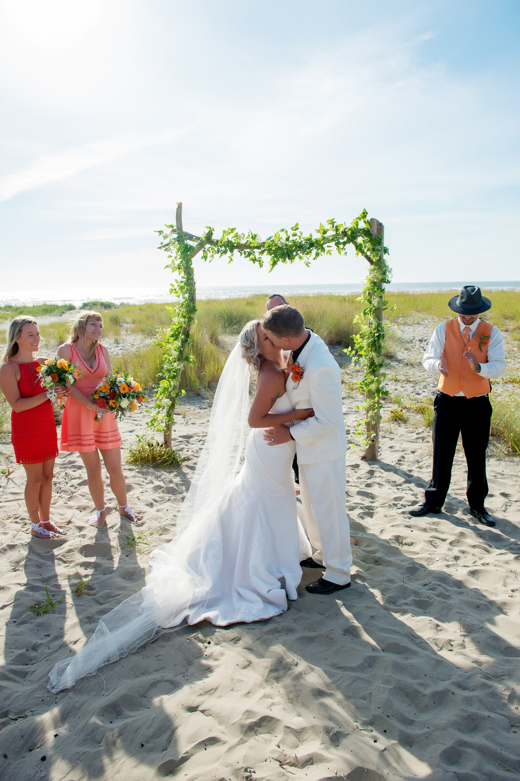 bride and groom kiss during wedding ceremony on seaside beach