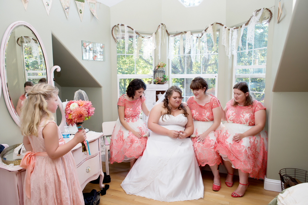 bridesmaids in pink lace dresses pray over bride