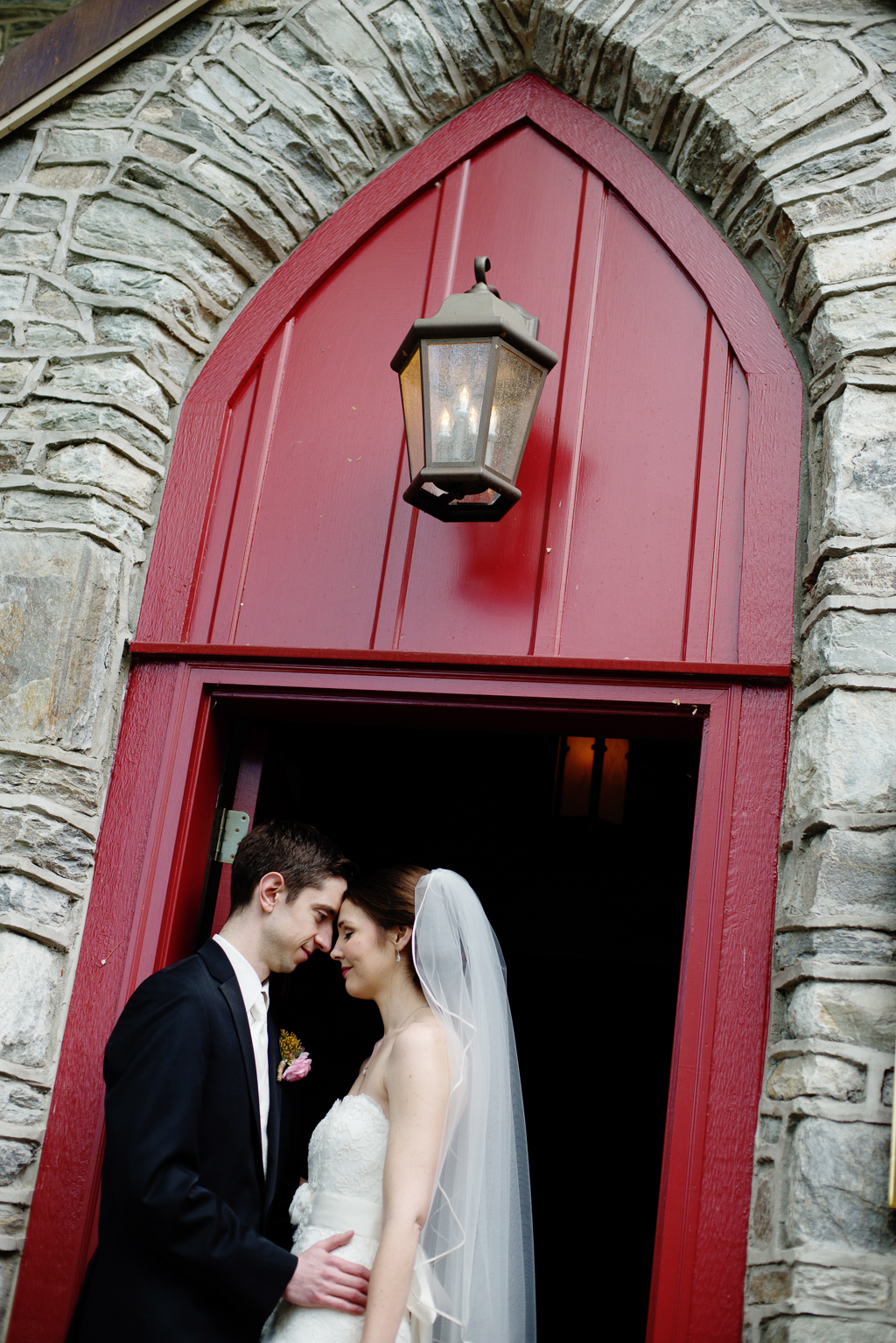 a bride and groom embrace under a large red door