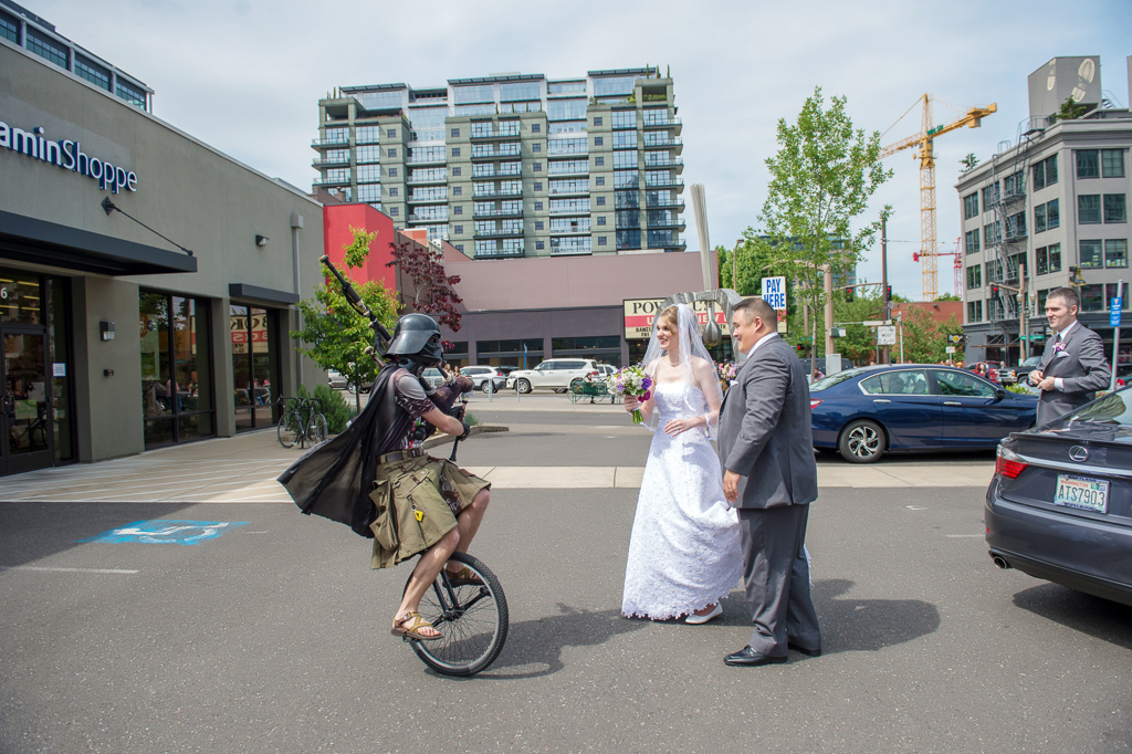 bride and groom look on as the unipiper rides around them in portland