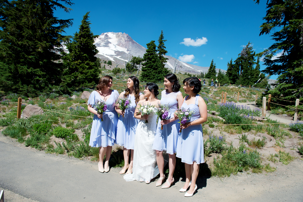 bridesmaids in purple dresses stand with bride in front of mount hood at timberline