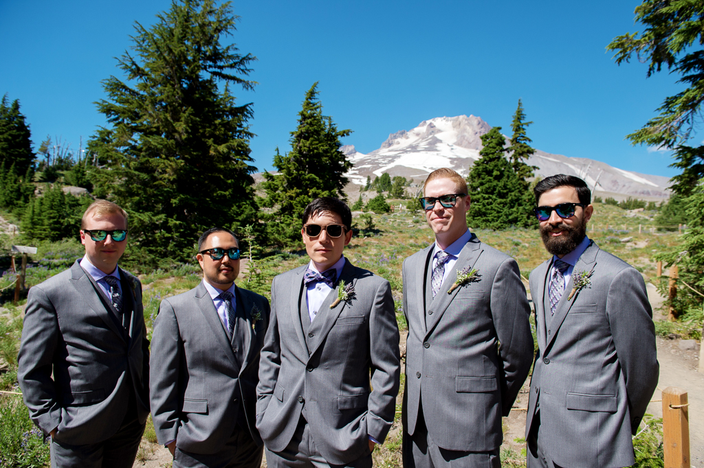 groomsmen in sunglasses and purple shirts stand in front of mt hood at timberline