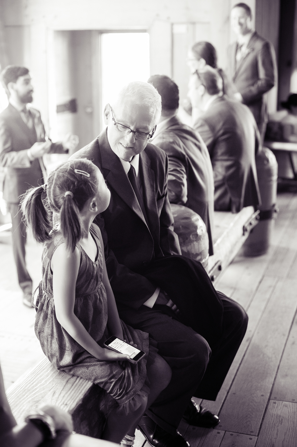 a grandpa looks at a little girl with pigtails as they wait for a wedding to start
