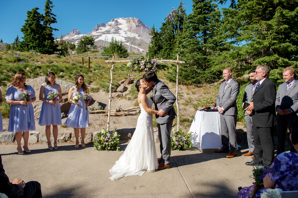 bride and groom have their first kiss as a married couple with mount hood in the background